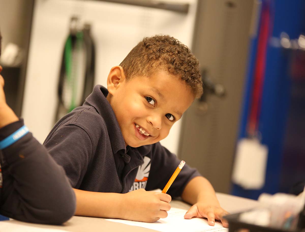 Elementary student smiling and posing together in a classroom.